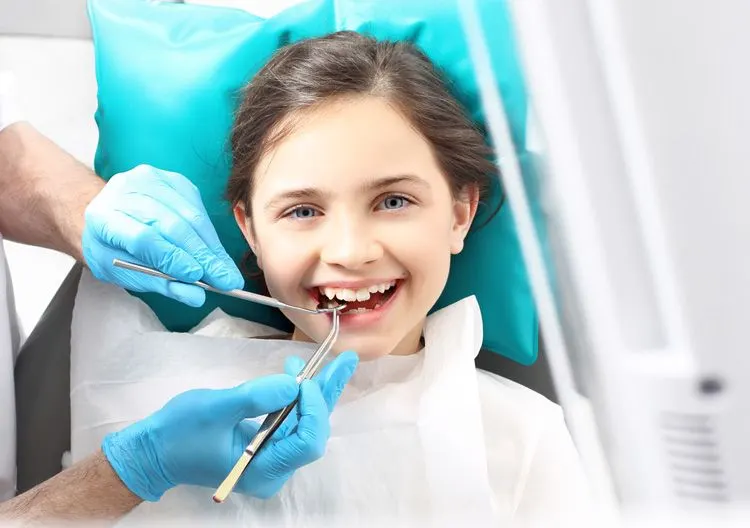 Smiling child sitting in a blue dental chair