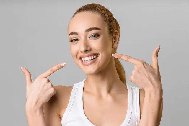 Woman smiling and pointing to her teeth